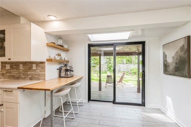 interior space with baseboards, a skylight, and light wood finished floors