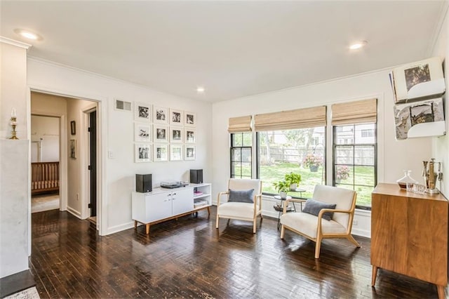 living area with wood-type flooring, crown molding, visible vents, and baseboards