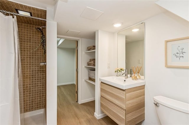bathroom with vanity, wood finished floors, a tile shower, and toilet