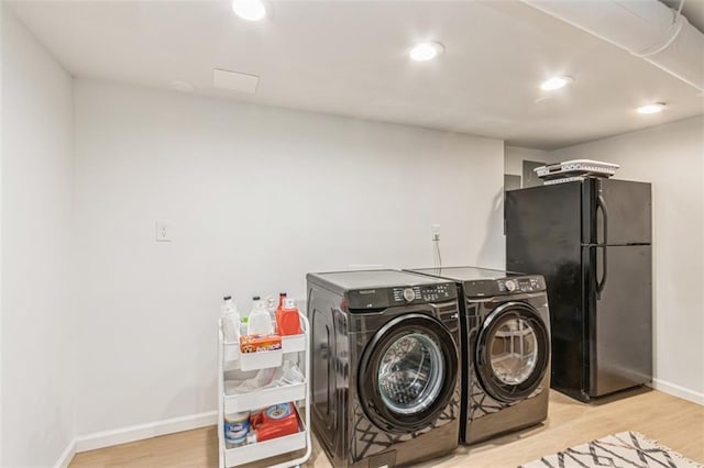 laundry area featuring baseboards, laundry area, wood finished floors, and washing machine and clothes dryer