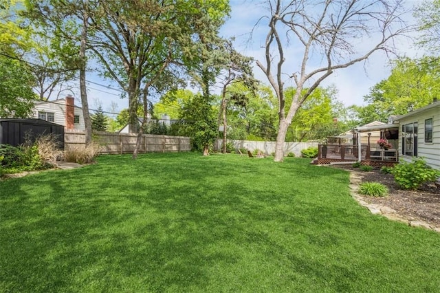 view of yard with an outbuilding, a fenced backyard, and a shed