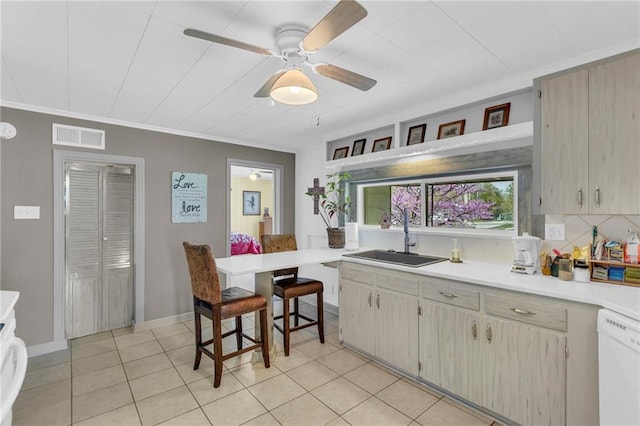 kitchen featuring visible vents, white dishwasher, light countertops, a sink, and light tile patterned floors