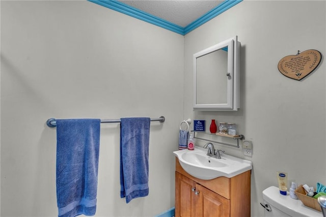 bathroom with vanity, ornamental molding, toilet, and a textured ceiling