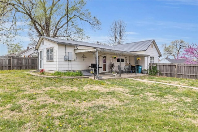 back of house featuring a fenced backyard, a yard, a patio area, and metal roof