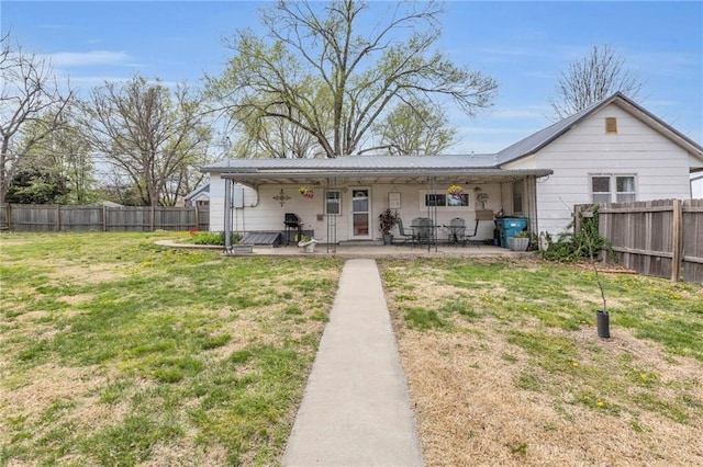 rear view of property with a lawn, a fenced backyard, a patio area, and metal roof