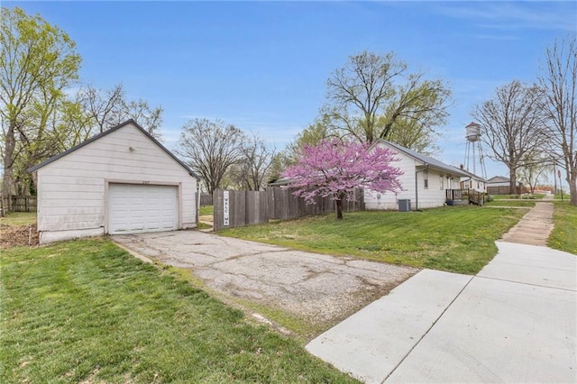 view of side of home featuring fence, a lawn, driveway, and a garage