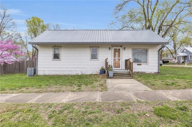 view of front facade with fence, metal roof, and a front yard