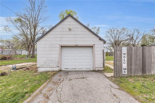 detached garage featuring fence and driveway