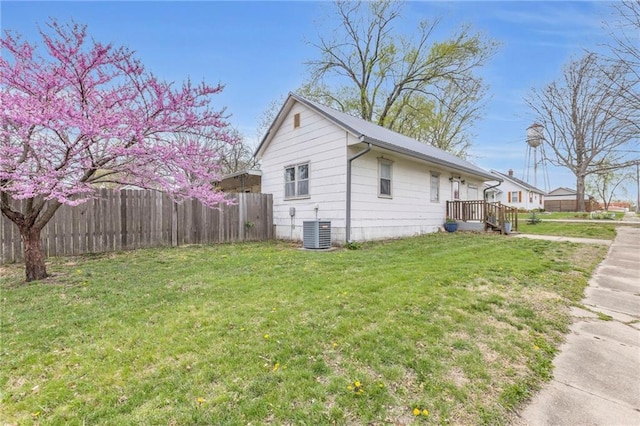 view of side of home featuring fence, a yard, and cooling unit