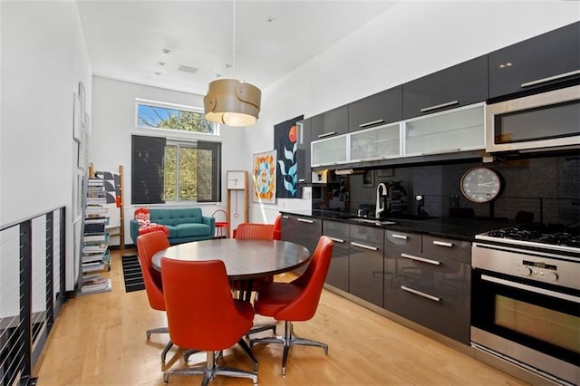 1610 Summit St, Kansas City, MO 64108 - kitchen featuring stainless steel appliances, tasteful backsplash, light wood-style floors, and modern cabinets