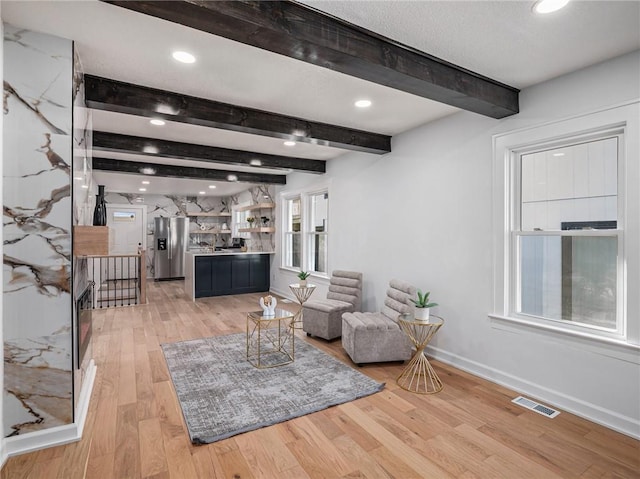 living room featuring visible vents, light wood finished floors, baseboards, recessed lighting, and beam ceiling