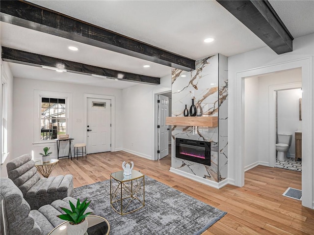 living area featuring baseboards, a fireplace, visible vents, and light wood-style floors
