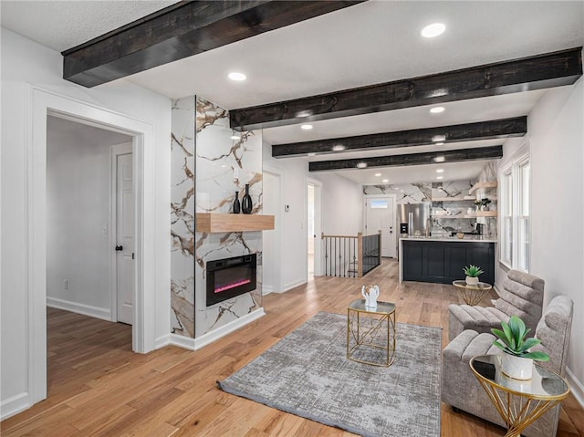 living room featuring baseboards, recessed lighting, beamed ceiling, and light wood finished floors