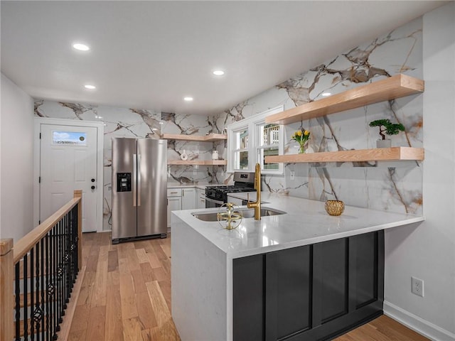 kitchen featuring light wood-type flooring, a peninsula, appliances with stainless steel finishes, and open shelves