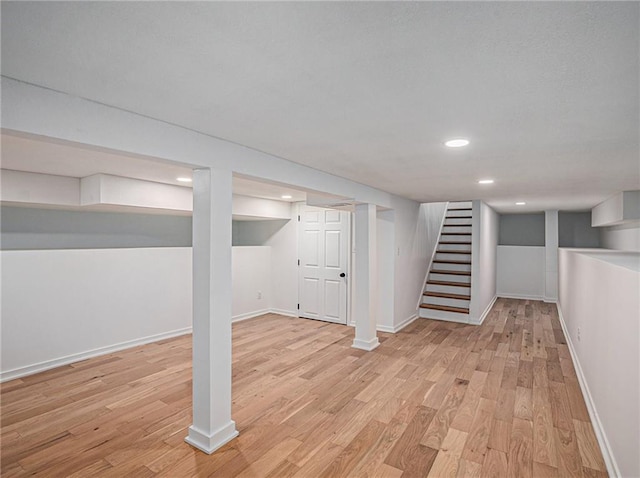 finished basement featuring baseboards, stairs, recessed lighting, and light wood finished floors