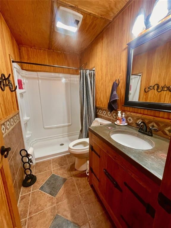518 SW Lakeside Dr, La Cygne, KS 66040 - bathroom featuring a shower stall, toilet, wooden ceiling, vanity, and wood walls