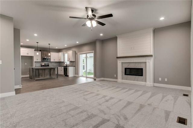 16827 W 164th Ter, Olathe, KS 66062 - unfurnished living room with recessed lighting, ceiling fan, light carpet, and a high end fireplace