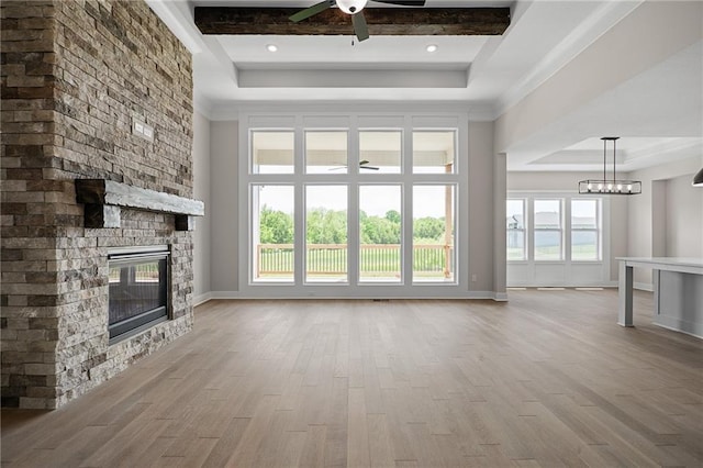 19389 W 114th Ter, Olathe, KS 66061 - unfurnished living room with a tray ceiling, a ceiling fan, a stone fireplace, wood finished floors, and crown molding
