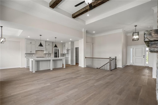 19389 W 114th Ter, Olathe, KS 66061 - unfurnished living room with light wood-style flooring, beam ceiling, a ceiling fan, recessed lighting, and a chandelier