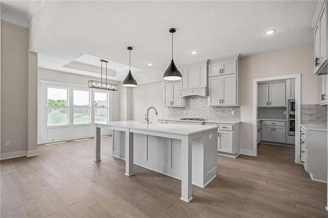 19389 W 114th Ter, Olathe, KS 66061 - kitchen featuring gas cooktop, light countertops, decorative backsplash, dark wood finished floors, and an island with sink