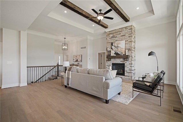 19389 W 114th Ter, Olathe, KS 66061 - living room featuring wood finished floors, a stone fireplace, a ceiling fan, beam ceiling, and a towering ceiling