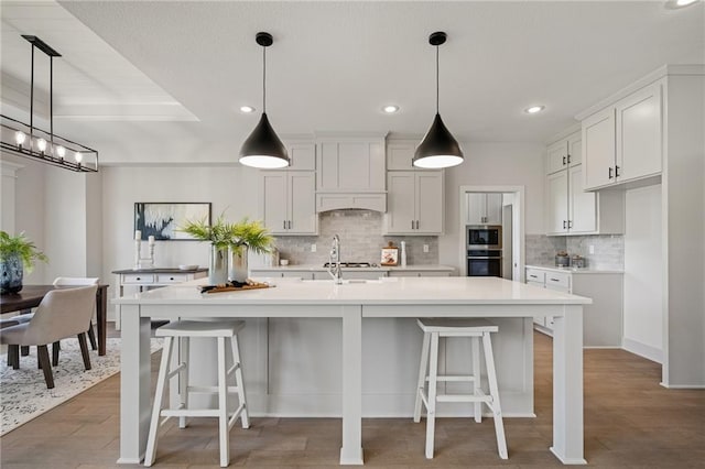 19389 W 114th Ter, Olathe, KS 66061 - kitchen with stainless steel appliances, backsplash, light countertops, white cabinetry, and a center island with sink