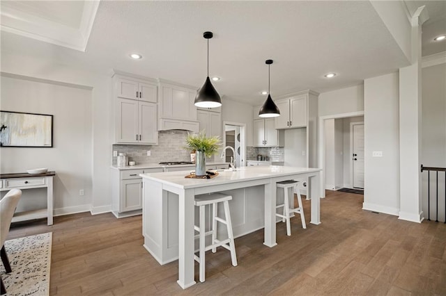 19389 W 114th Ter, Olathe, KS 66061 - kitchen with backsplash, light countertops, wood finished floors, recessed lighting, and a center island with sink