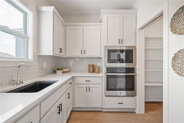 19389 W 114th Ter, Olathe, KS 66061 - kitchen with oven, built in microwave, light wood-style flooring, light countertops, and backsplash