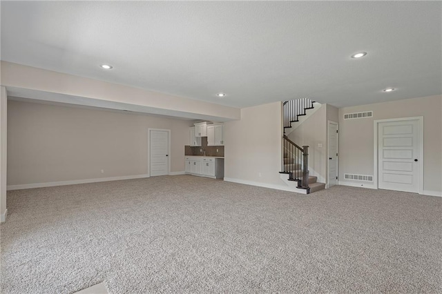 19389 W 114th Ter, Olathe, KS 66061 - unfurnished living room with light colored carpet, stairway, and recessed lighting