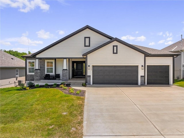19389 W 114th Ter, Olathe, KS 66061 - view of front of home with covered porch, a garage, concrete driveway, a front yard, and stone siding