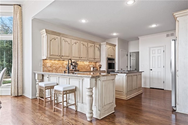 4319 N Mulberry Dr, Kansas City, MO 64116 - kitchen featuring dark wood finished floors, stainless steel appliances, tasteful backsplash, and visible vents