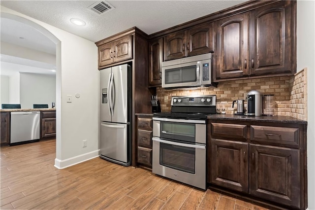 4319 N Mulberry Dr, Kansas City, MO 64116 - kitchen with baseboards, visible vents, backsplash, dark countertops, and appliances with stainless steel finishes