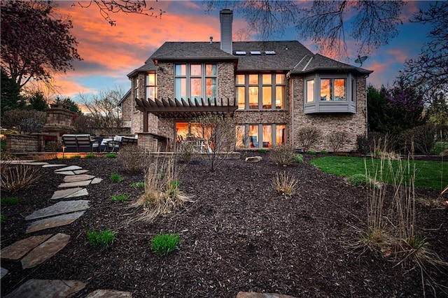 4319 N Mulberry Dr, Kansas City, MO 64116 - back of property at dusk with brick siding, a patio, a chimney, and a pergola