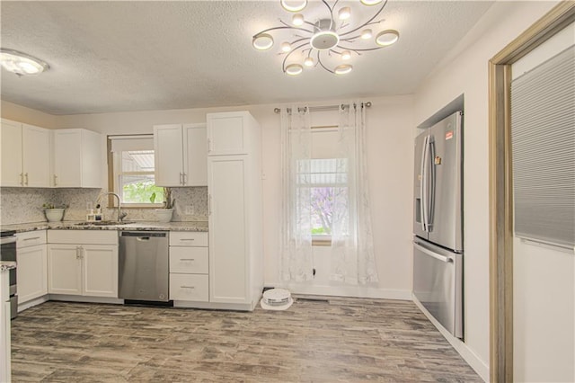 435 NE 41st Ter, Kansas City, MO 64116 - kitchen featuring an inviting chandelier, a sink, a textured ceiling, white cabinetry, and stainless steel appliances