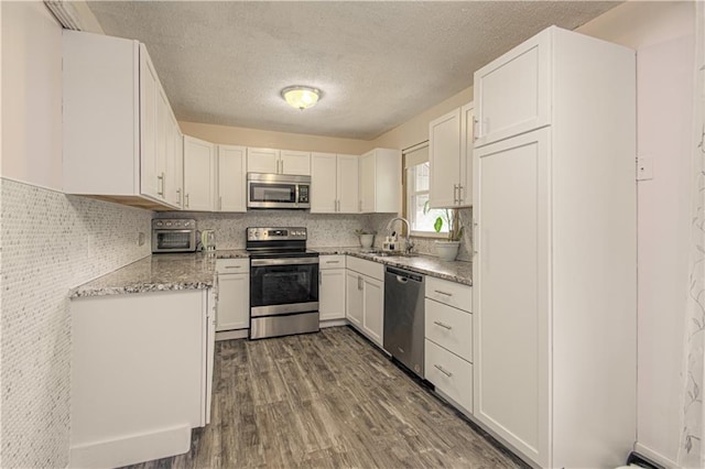435 NE 41st Ter, Kansas City, MO 64116 - kitchen with a textured ceiling, white cabinets, a sink, stainless steel appliances, and dark wood-style floors