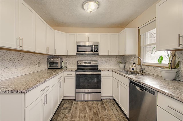 435 NE 41st Ter, Kansas City, MO 64116 - kitchen featuring a sink, white cabinets, a textured ceiling, and stainless steel appliances