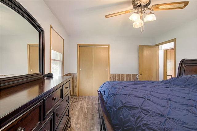 435 NE 41st Ter, Kansas City, MO 64116 - bedroom featuring a closet, light wood-type flooring, wainscoting, and a ceiling fan