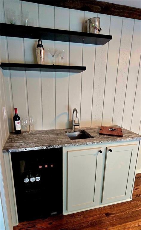 bar with dark wood-style flooring, wet bar, a sink, and wine cooler