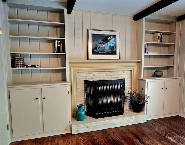 unfurnished living room with built in features, beamed ceiling, and dark wood finished floors