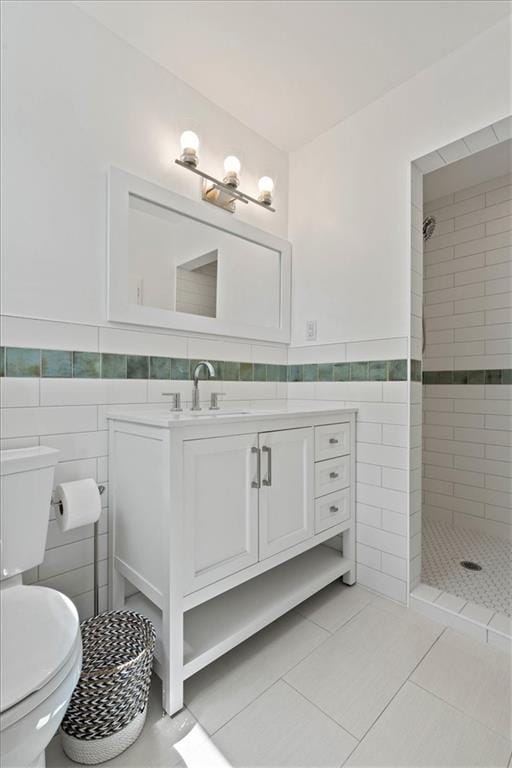 full bathroom with tile patterned flooring, vanity, toilet, tile walls, and tiled shower