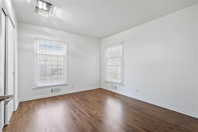empty room with baseboards, visible vents, and wood finished floors