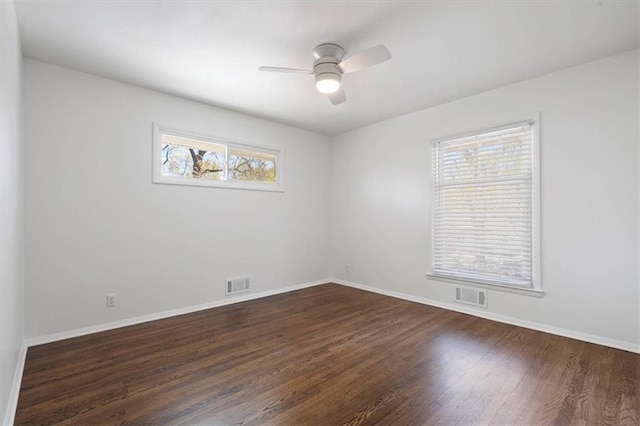 spare room featuring baseboards, a ceiling fan, dark wood-style flooring, and visible vents