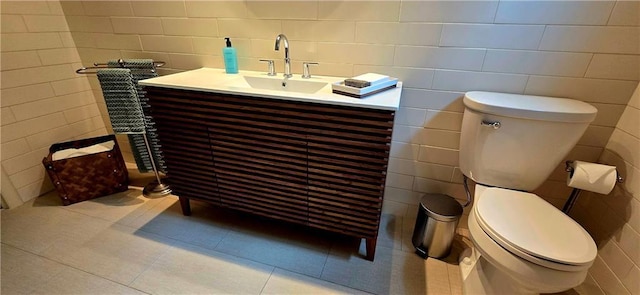 bathroom featuring vanity, tile patterned flooring, toilet, and tile walls