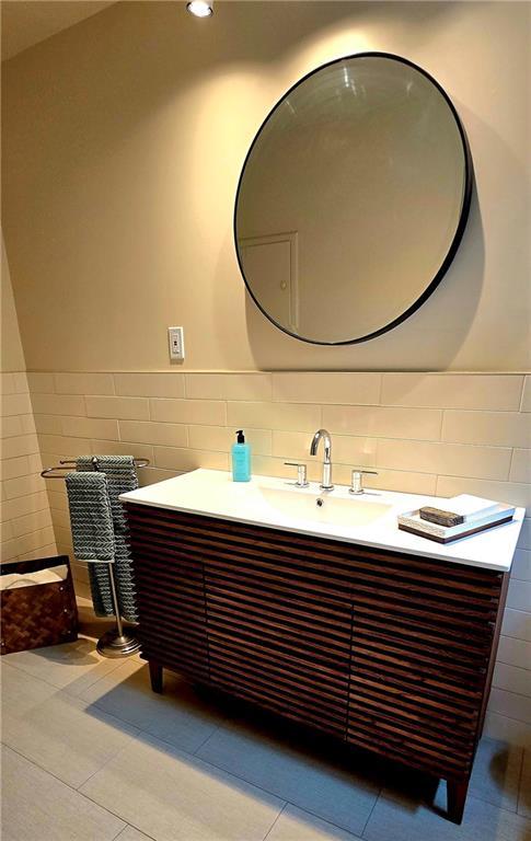 bathroom with tile walls, tile patterned flooring, a wainscoted wall, and vanity