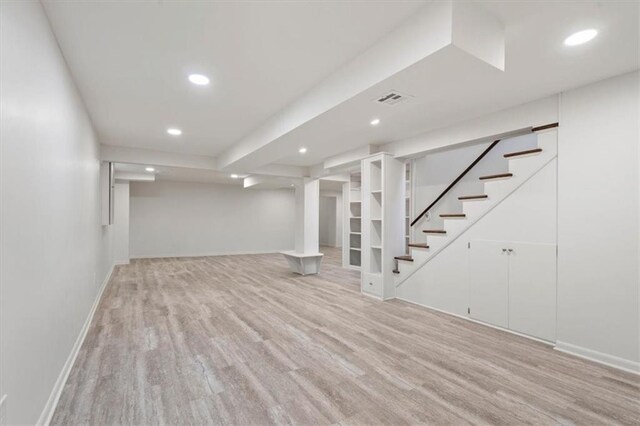 finished below grade area featuring recessed lighting, baseboards, light wood-type flooring, visible vents, and stairway
