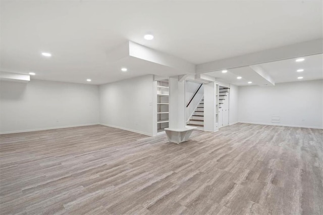 finished basement featuring baseboards, recessed lighting, stairway, and light wood-type flooring