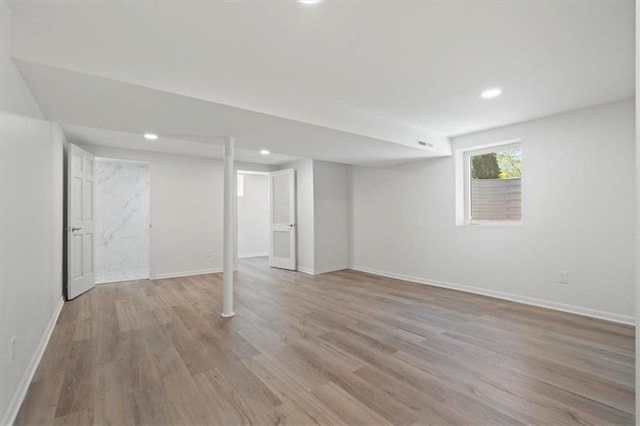 below grade area with recessed lighting, light wood-style flooring, baseboards, and visible vents