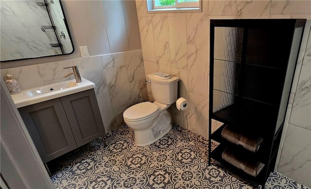 bathroom with tile walls, vanity, and toilet