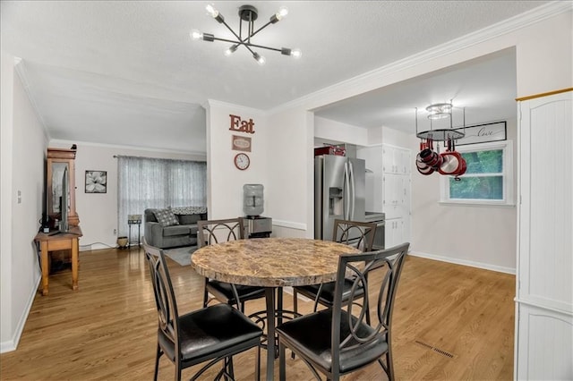 1477 Spruce Ave, Liberty, MO 64068 - dining area with light wood-style flooring, baseboards, an inviting chandelier, and crown molding
