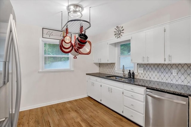 1477 Spruce Ave, Liberty, MO 64068 - kitchen with light wood-type flooring, white cabinetry, decorative backsplash, stainless steel dishwasher, and a sink
